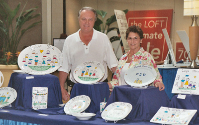Carol of Carol Creations with husband, Thomas Hogue, at a show - Carol Creations is the creator of hand-painted, custom crafted plates, platters, hot plates, mugs and more.  Carol Creations starts with high quality porcelain dinner and tableware that is then hand-painted.  After painting, each item is oven fired for durability.  Each figure is customized to resemble family members or friends with hair color and style, and other distinguishing characteristics.  Carol Creations custom painting makes these truly special and unique gifts for holidays, baby showers, weddings, birthdays . . . gifts for someone special anytime.  